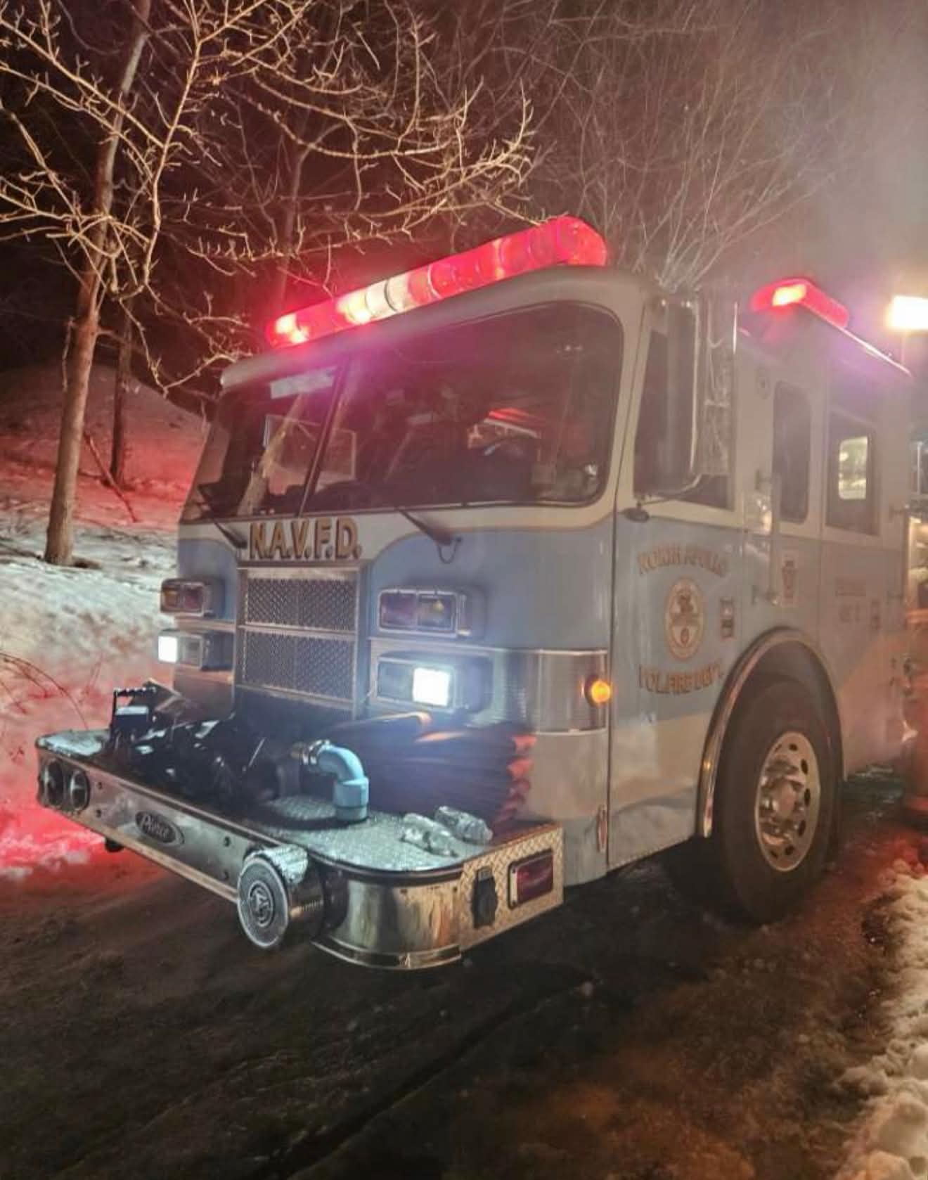 Department engine with red warning lights running at a night call in the snow